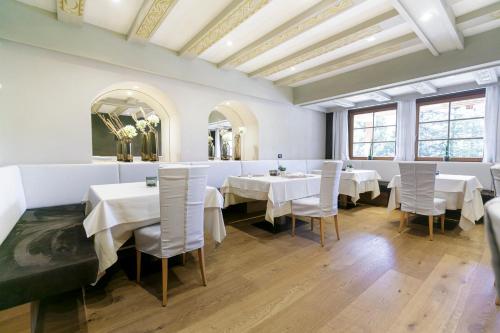a dining room with white tables and white chairs at Hotel Gran Paradiso in San Cassiano