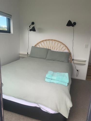 a bedroom with a bed with two towels on it at Hosts on the Coast Admirals Gold in Cooks Beach