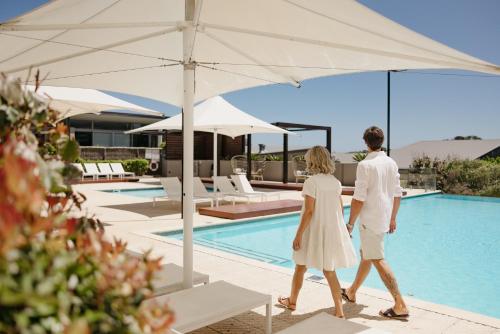 a man and woman walking by a swimming pool at Smiths Beach Resort in Yallingup