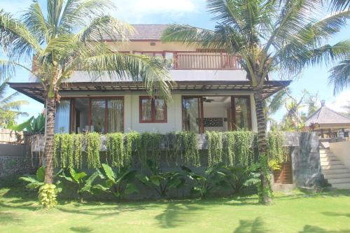una casa con palmeras delante en Beach Villa Balian, en Selemadeg