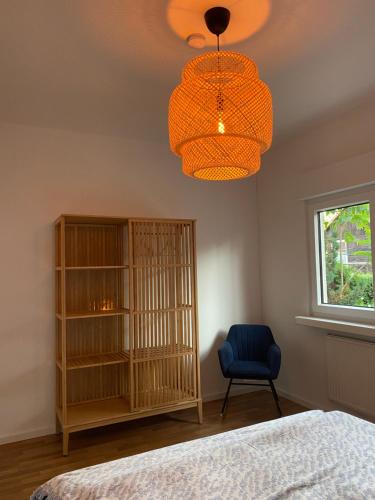 a bedroom with a bed and a chair and a chandelier at NEU: Grüne Idylle nahe Hauptbahnhof & Hufeisensee in Halle an der Saale