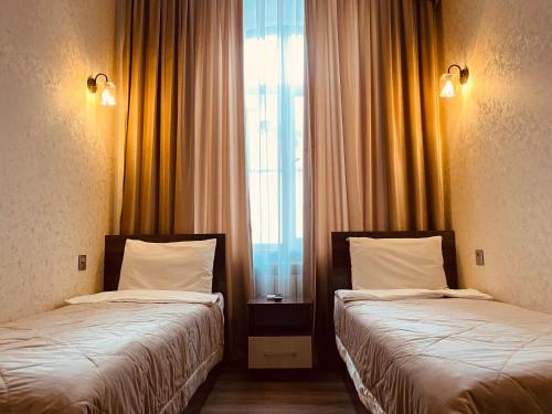 two beds in a hotel room with a window at Moss Art Boutique Hotel in Baku