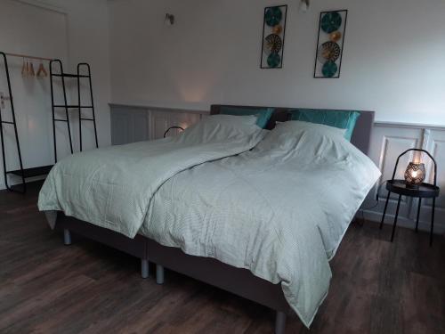 een slaapkamer met een groot bed met witte lakens bij B&B D'n Optie in Druten