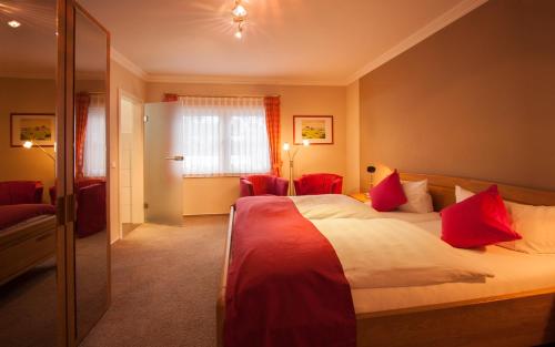 ein Hotelzimmer mit einem großen Bett mit roten Kissen in der Unterkunft Landgasthof Schneider, Westfeld in Schmallenberg