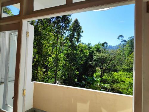 an open window with a view of trees at Queensark in Nallathanniya