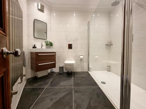 a bathroom with a tub and a toilet and a sink at Luxury 2 bedroom city centre apartment with panoramic views and high ceilings in Aberdeen