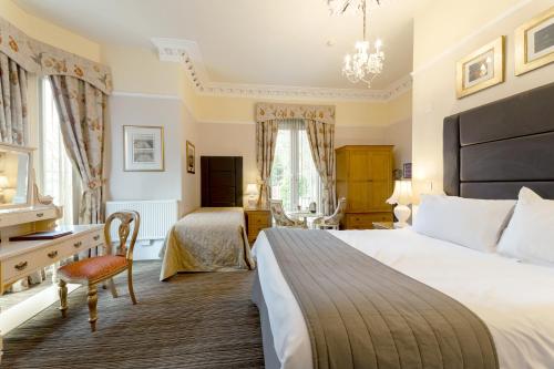 a hotel room with a bed, chair, table and lamps at Charades Guest House in Hereford