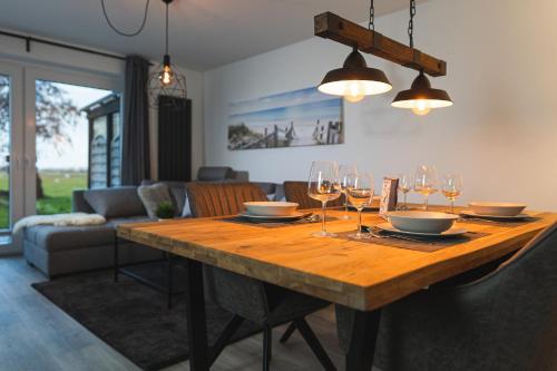 una mesa de madera con copas de vino y platos en ella en Ferienwohnung Landblick, en Emmelsbüll-Horsbüll