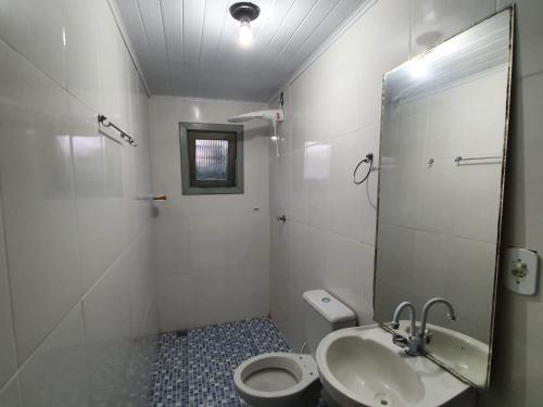 a bathroom with a toilet and a sink and a mirror at Sitio Barth in Porto Seguro
