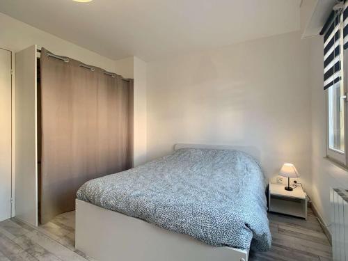 ein Schlafzimmer mit einem Bett mit einer blauen Decke darauf in der Unterkunft Charmant studio centre ville de Mutzig in Mutzig