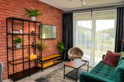 a living room with a green couch and a brick wall at Apartament LOFTSPA in Ustrzyki Dolne