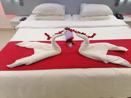 two swans are laying on a red blanket on a bed at Beach Grand & Spa Premium in Hulhumale