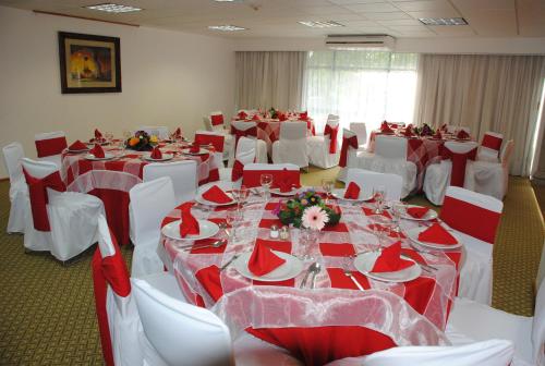 a room with tables and chairs with red and white linens at Hotel & Suites PF in Mexico City