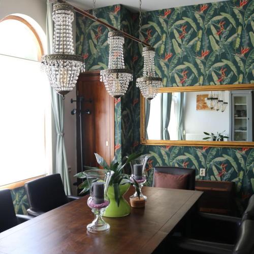 a dining room table with a mirror and chandeliers at The Dutch Hills in Gulpen