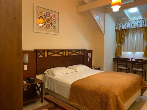 a bedroom with a large bed and a desk at Hotel Pousada Ald' Mama in Gramado
