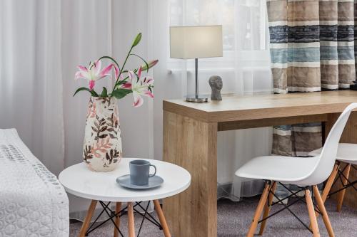 a room with a table and a vase with pink flowers at Willa 777 Krasickiego in Międzyzdroje