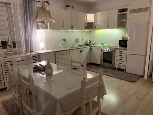a kitchen with a table with chairs and a white refrigerator at Prima House in Podgorica