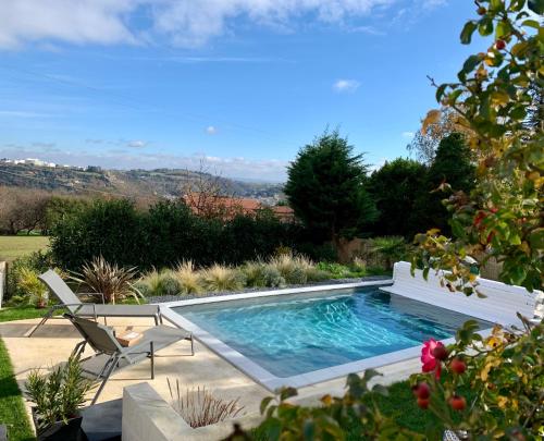 a swimming pool with two chairs and a bench at La Glycine B&B in Sainte-Colombe