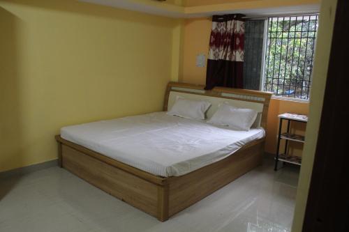 a bedroom with a bed with white sheets and a window at Alpine Green in Rānchī