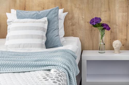a bed with a vase of purple flowers on a table at Willa 777 Krasickiego in Międzyzdroje