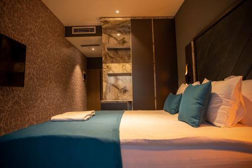 a bedroom with a large bed with blue and white pillows at Palace Hotel & SPA in Mitrovicë