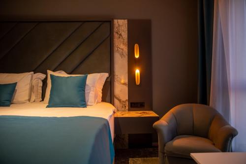 a hotel room with a bed and a chair at Palace Hotel & SPA in Mitrovicë