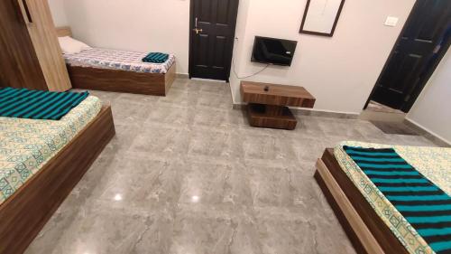 a room with three beds and a tv in it at Godwill Kimo Guest house Seraulim in Madgaon