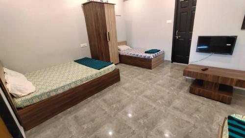 a room with two beds and a tv in it at Godwill Kimo Guest house Seraulim in Madgaon