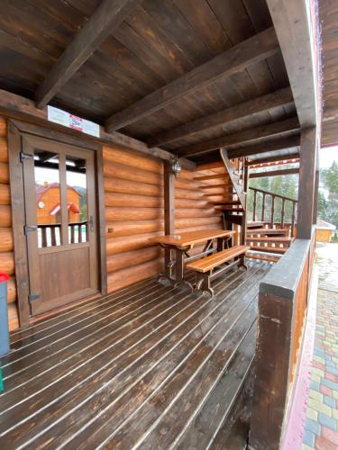 a porch of a cabin with a wooden door and a bench at Plavianska Sadyba in Plav'ya