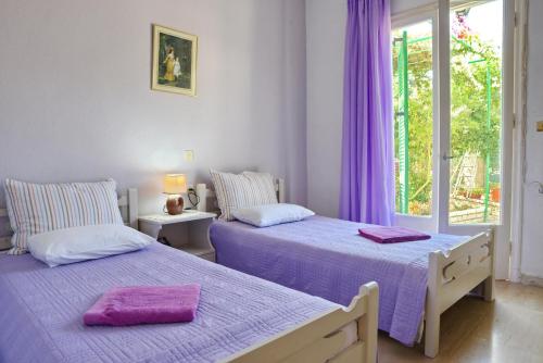 2 Betten in einem Zimmer mit lila Vorhängen in der Unterkunft Babis - LOGGOS APARTMENTS in Longós