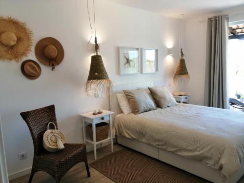 a bedroom with a bed and a chair and a window at OCEAN TERRACES by VILA GAIVOTA D in Ferragudo
