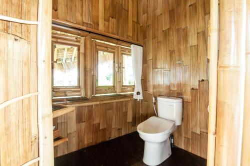 ein Holzbadezimmer mit einem WC und 2 Fenstern in der Unterkunft Magic Hills Bali - Magical Eco-Luxury Lodge in Selat