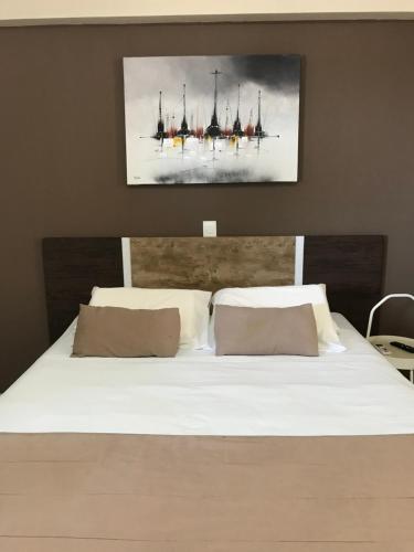 ein Schlafzimmer mit einem weißen Bett und einem Gemälde an der Wand in der Unterkunft Marsallis Praia - Flat 404 - Vista Mar in Natal