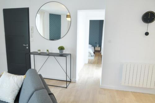 ein Wohnzimmer mit einem grauen Sofa und einem Spiegel in der Unterkunft T2 de 55m2 avec toit terrasse, hyper centre, wifi, draps, savons et serviettes fournis in Cognac