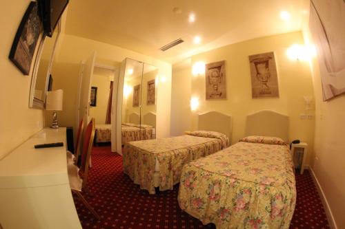 a hotel room with two beds and a mirror at Hotel Europa Fiera in Rho