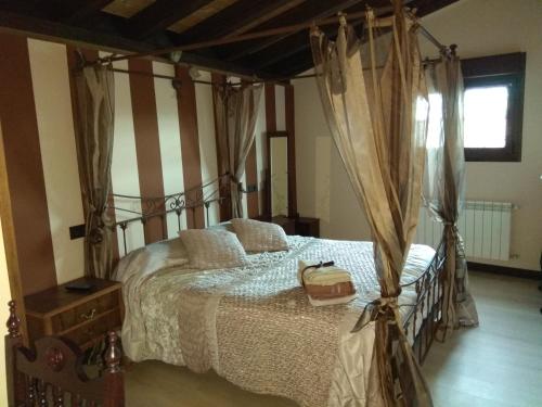 La Cerca de Doña Jimena في Modúbar de San Cibrián: غرفة نوم بها سرير مظلة مع حقيبة عليها