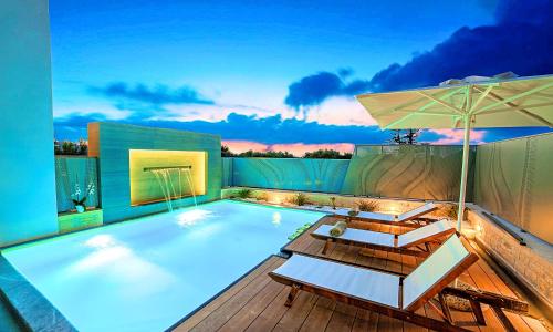 a swimming pool with chairs and an umbrella at Perla Villas with Heated Pool in Kávallos