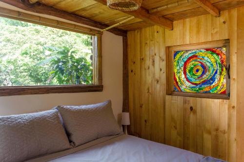 a bedroom with a bed with a painting on the wall at Cabana del Rio Lejos Pijao, Finca Flora del Rio in Pijao