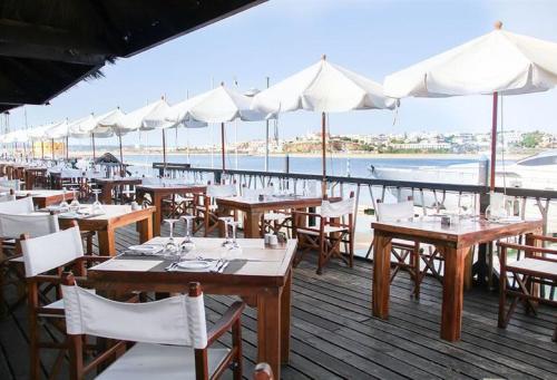 a restaurant with tables and white umbrellas on a deck at OCEAN TERRACES by VILA GAIVOTA D in Ferragudo