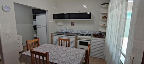 una pequeña cocina con mesa, mesa y sillas en Lindo Sobrado c/ Piscina e conforto próximo do mar en Itapoa