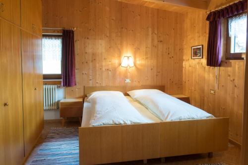 a bedroom with a bed in a wooden wall at Ciasa Torneri in San Vigilio Di Marebbe