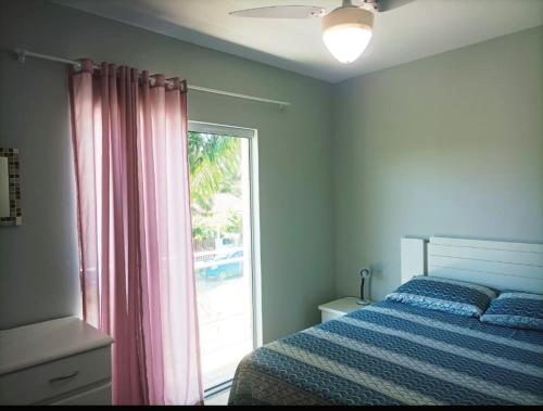 a bedroom with a bed and a large window at Lindo Sobrado c/ Piscina e conforto próximo do mar in Itapoa