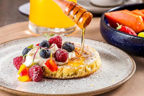 Un postre con fruta en un plato con un chorrito de miel. en Casa Marambaia Hotel, en Petrópolis