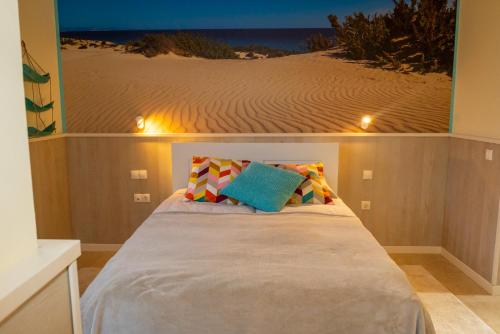 sypialnia z łóżkiem i zdjęciem plaży w obiekcie Lucky Thirteen - Apartment with Ocean View w mieście Caleta De Fuste
