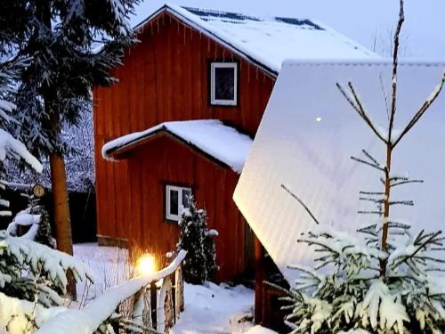 a red barn with snow on the roof at Villa nagori in Slavske