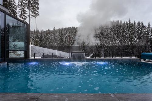 a swimming pool with a fountain in the snow at GirskiDelux in Bukovel