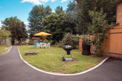 a grill in a yard with a table and umbrella at Cocottes & Colibri in Châtellerault