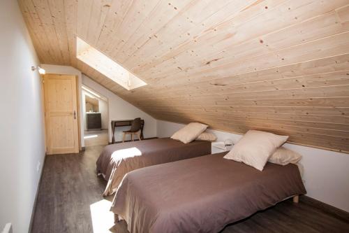 two beds in a room with a wooden ceiling at Entre Lac et Montagnes in Faverges