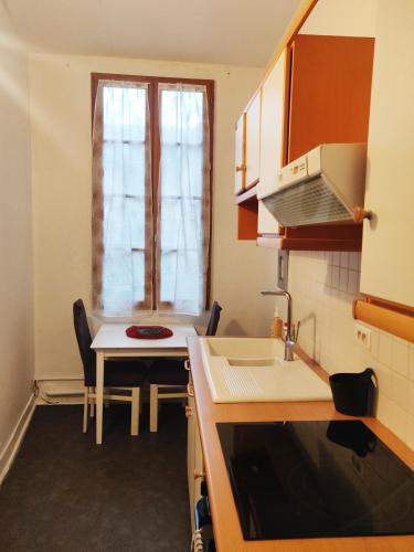 une cuisine avec un évier, une table et une fenêtre dans l'établissement 2 chambres 88m2 Extra centre historique Cahors vaste appartement convivial et cosy, à Cahors