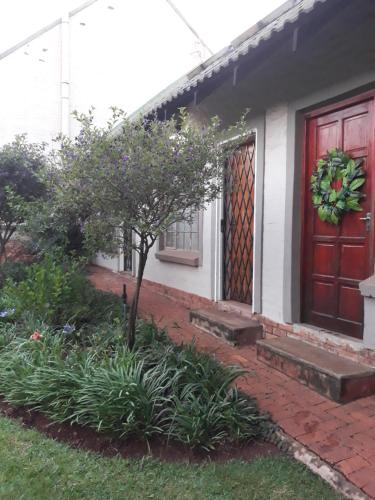 a house with a red door and a tree at African Silhouette Guesthouse in Benoni